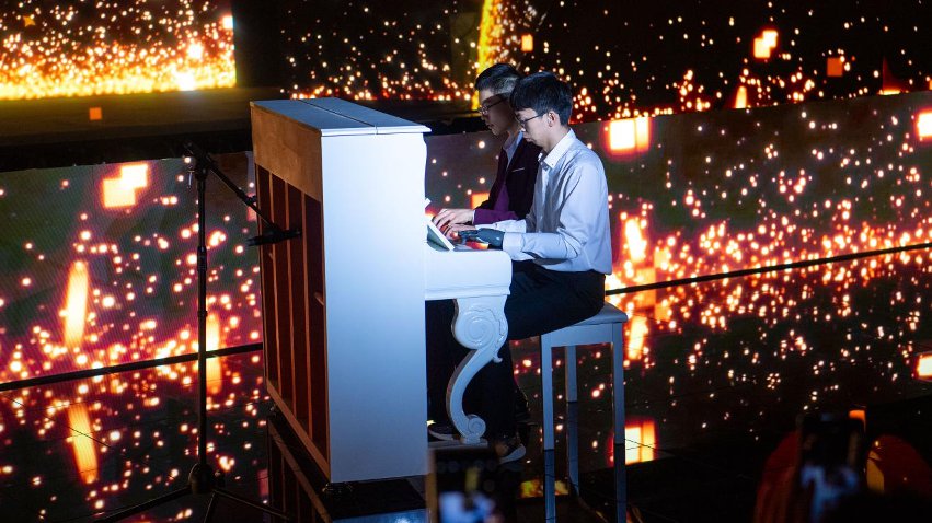 智能仿生手使用者古月與少年鋼琴家舒海峰合奏。主辦方供圖